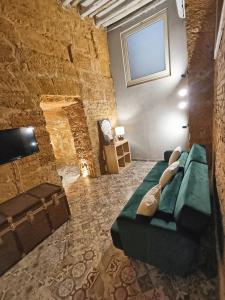 a living room with a green couch in a stone wall at Historic Center Apartment in Agrigento