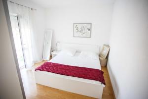una camera da letto bianca con un letto bianco e una coperta rossa di Villa Oleander a Marina