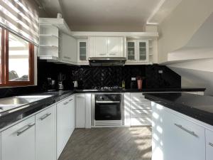 a kitchen with white cabinets and black counter tops at Luxury Villa with Jacuzzi in Baños