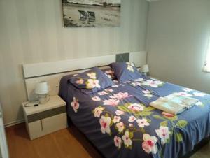 a bed with a blue comforter with flowers on it at Apartamento SIGÜEIRO CAMINO INGLÉS (English Way) in Sigüeiro