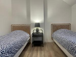 dwa łóżka w pokoju z lampką na stole w obiekcie Appart Balcon Clim 10 mins Disneyland 2CHB QuartierChic w mieście Serris