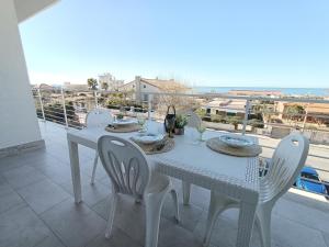 a white table and chairs on a balcony with a view at Modern Apartment - Fronte Mare in Focene
