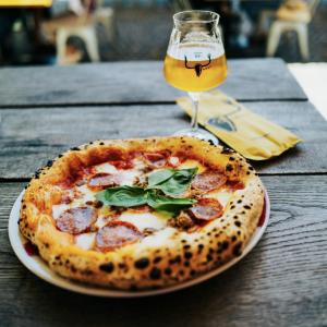 une pizza sur une table avec un verre de bière dans l'établissement Room in BB - Stanza in affitto Giarre, à Giarre