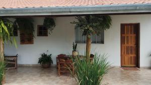 Cette maison blanche dispose d'une terrasse ornée de plantes et d'une porte. dans l'établissement Casa flores do campo, à Campos do Jordão