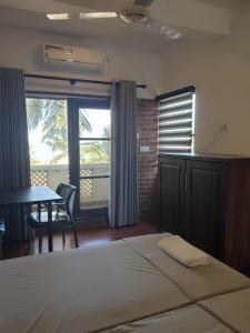 a bedroom with a bed and a table and a window at Janishi Residencies in Negombo