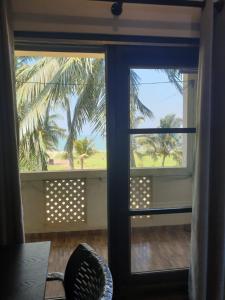 una ventana con vistas a una palmera en Janishi Residencies en Negombo