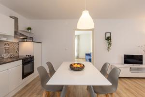 eine Küche und ein Esszimmer mit einem weißen Tisch und Stühlen in der Unterkunft Apartmani Bašić 2 in Njivice