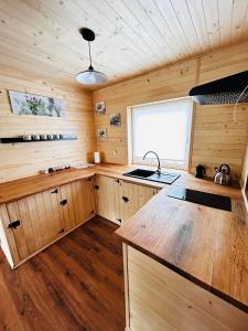 cocina con armarios de madera, fregadero y ventana en Domek na Skarpie 2, en Joniec