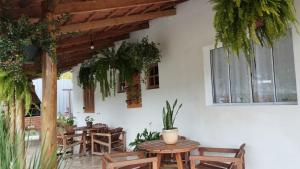 eine Terrasse mit Tischen, Stühlen und Pflanzen in der Unterkunft Casa flores do campo in Campos do Jordão