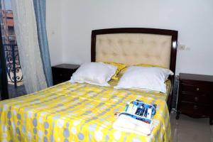 a bedroom with a bed with a yellow comforter at Home By Dina'Sty in Yaoundé