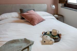 a bed with a tray of cosmetics and a tray of cups at Varesina Suite - Pavia City Center - by Host4U in Pavia