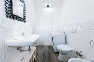 uma casa de banho branca com um lavatório e um WC em Brezza Marina - Porto Cesareo em Porto Cesareo