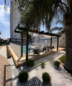 een patio met tafels en stoelen en een palmboom bij APTO frente mar com vista incrível e com piscina! in Piçarras