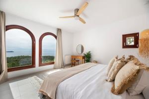 a white bedroom with a large bed with windows at Sea La Vie - Stunning Sea and Jungle Views in San Antonio