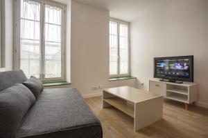 uma sala de estar com um sofá e uma televisão de ecrã plano em Centre-ville - calme -proche gare em Angoulême