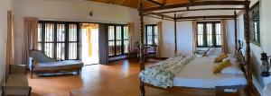 a bedroom with a bed and a chair and windows at Baycliff Cottages in Varkala