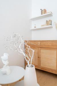 eine weiße Vase mit einem Baum im Wohnzimmer in der Unterkunft Grand Central 1845 - 2 Bedrooms Design Flat in Bergamo