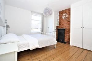 a white bedroom with a bed and a fireplace at Cosy 2 bedroom Victorian townhouse in the town Centre in Bury Saint Edmunds