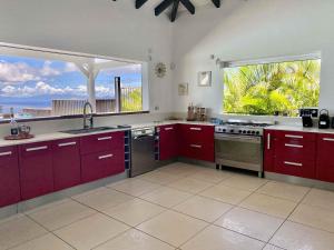 cocina con armarios rojos y vistas al océano en Villa Horizon à Marie-Galante en Grand-Bourg