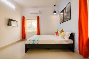 a bedroom with a bed with orange curtains at OYO Flagship Saket Homes in Bhubaneshwar