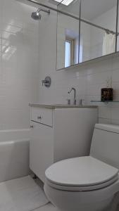 a white bathroom with a toilet and a sink at The Central Park West by Amsterdam Avenue in New York