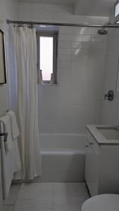 a white bathroom with a shower curtain and a sink at The Central Park West by Amsterdam Avenue in New York