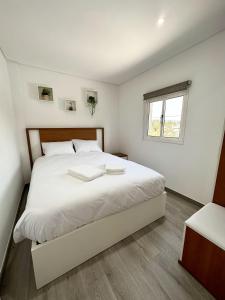 a bedroom with a large white bed with a window at Cantinho do Vale - Oleiros in Oleiros