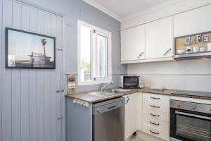 een keuken met witte kasten, een wastafel en een raam bij Apartamento en Cala en Porter, Menorca. in Cala'n Porter