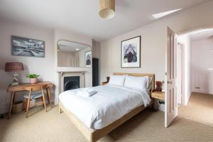 a bedroom with a bed and a table and a fireplace at Stylish Victorian 2 Bed Terraced House with Garden in Cambridge