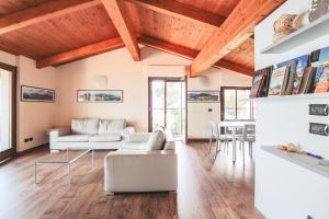 a living room with white furniture and wooden ceilings at Appartamento Al Porto in Pianello Del Lario