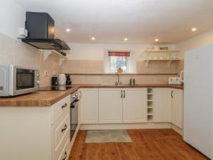 a kitchen with white cabinets and a microwave at Dunridge Cottage in Yelverton