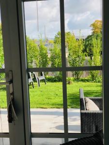 a sliding glass door with a view of a yard at Bel Air Studios-Terrasse couverte-Jardinet-Vue Pont de Normandie-Parking privé in Honfleur