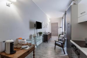 una cucina e un soggiorno con pareti bianche e tavolo di Casa Ugo - Pavia City Center - by Host4U a Pavia