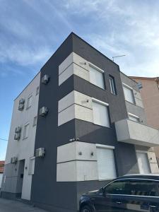 a black and white building with a car parked in front at Lux apartment Bijeljina in Bijeljina