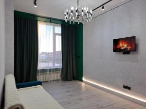 INJU Arena 1-rooms apartments في أستانا: غرفة معيشة مع أريكة وتلفزيون على الحائط