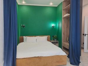 INJU Arena 1-rooms apartments في أستانا: غرفة نوم بحائط أخضر وسرير