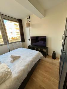 um quarto com uma cama grande e uma televisão em Le Secret de l'Architecte : proche Centre et Gare em Dijon