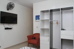 ein Wohnzimmer mit einem roten Stuhl und einem TV in der Unterkunft " Le Nid Douillet ", un fabuleux studio, calme, cosy et bien climatisé au centre de saly in Saly Portudal