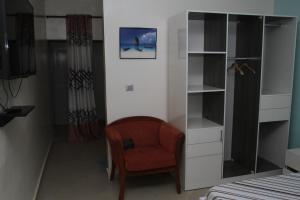 a bedroom with a chair and a book shelf at " Le Nid Douillet ", un fabuleux studio, calme, cosy et bien climatisé au centre de saly in Saly Portudal