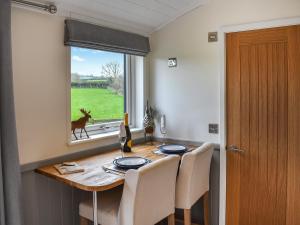 a dining room table with a deer looking out the window at Greengill Farm Shepherds Hut- Ukc3632 in Gilcrux