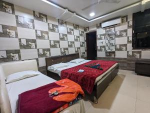 a bedroom with two beds and a wall with pictures at Hotel Shikhar Inn in Ujjain