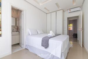 ein weißes Schlafzimmer mit einem Bett und einem Handtuch darauf in der Unterkunft Casa Duplex próxima à Praia em Porto - ROC0265 in Porto Seguro