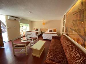 a room with two beds and a couch and a table at Hotel Medrano Temáticas and Business Rooms Aguascalientes in Aguascalientes