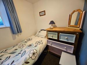 a bedroom with a bed and a dresser and a mirror at Talarfor Barmouth in Barmouth