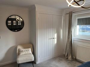 Habitación blanca con silla y espejo en Glenshellach Apartment Oban en Oban