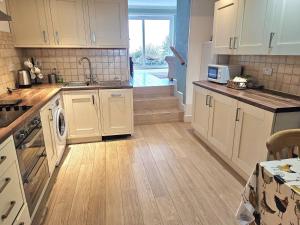 a kitchen with white cabinets and a wooden floor at Talarfor Barmouth in Barmouth