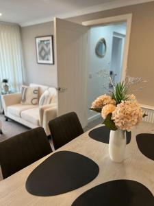 Glenshellach Apartment Oban في أوبان: طاولة غرفة الطعام مع إناء من الزهور عليها