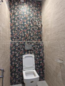 a bathroom with a toilet with a floral wallpaper at Hotel Shikhar Inn in Ujjain