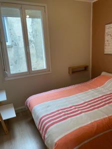 a bedroom with a bed with a striped comforter and two windows at Une escale à Boulogne - Appartement au coeur de la ville avec Parking privé in Boulogne-sur-Mer