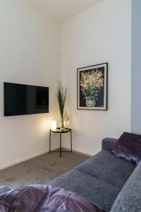 a living room with a couch and a tv on a wall at TWINSTAY in Catania